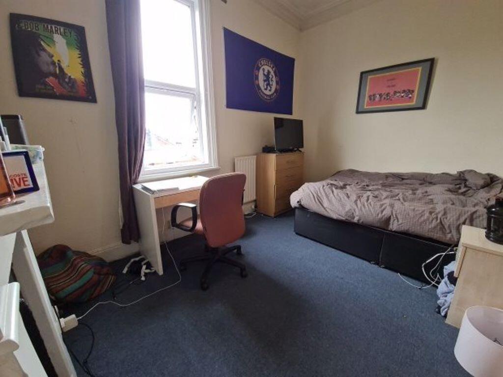 A cozy student bedroom featuring a bed, a desk,...