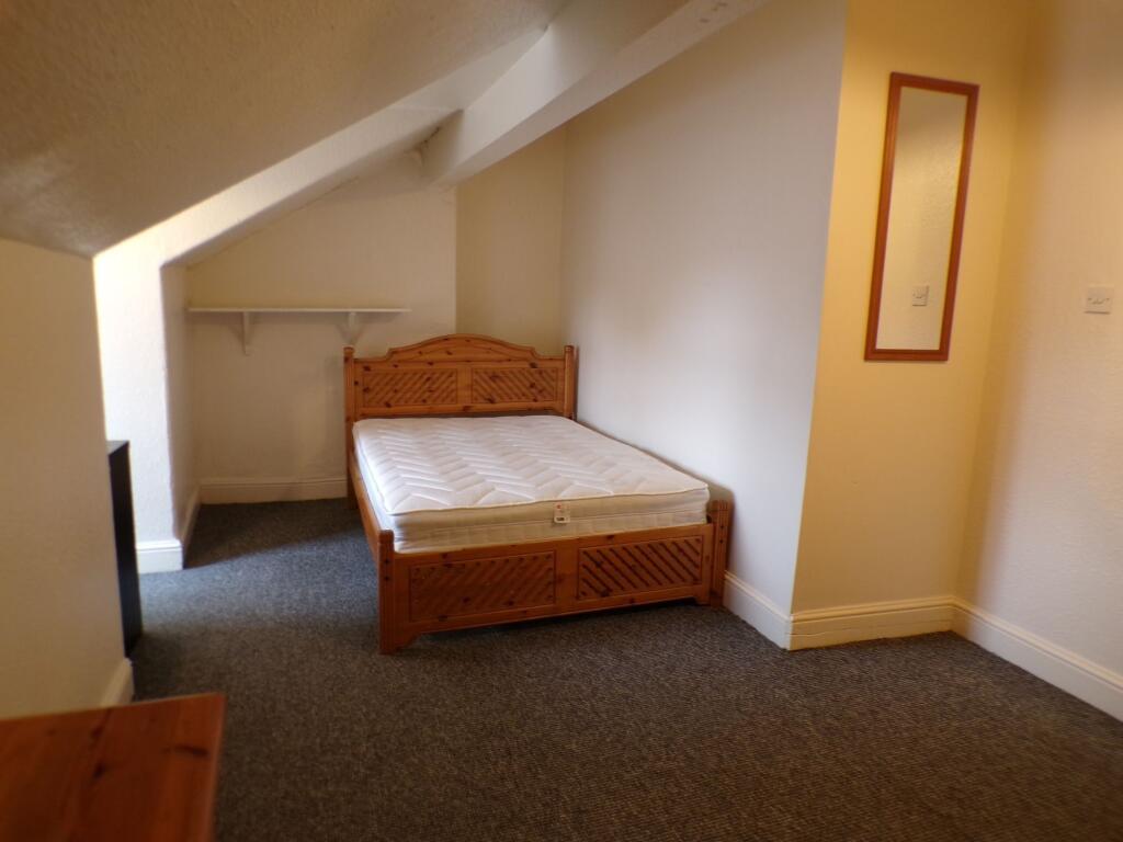 A cozy single bedroom with sloped ceiling, feat...