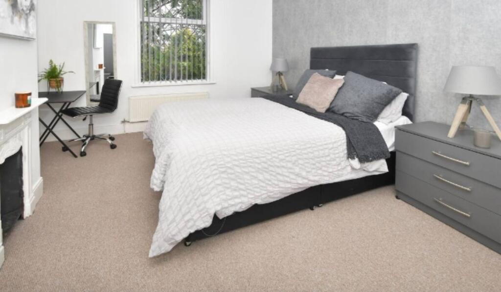 A modern, well-lit bedroom featuring a large be...