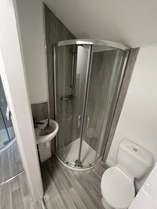 A modern bathroom featuring a curved glass show...
