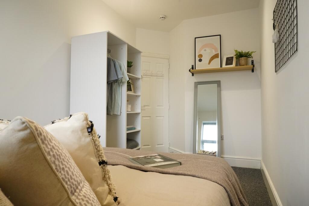 A cozy, well-lit bedroom featuring a comfortabl...