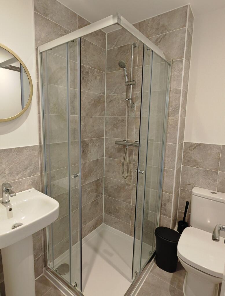Modern bathroom featuring a clean, glass-enclos...