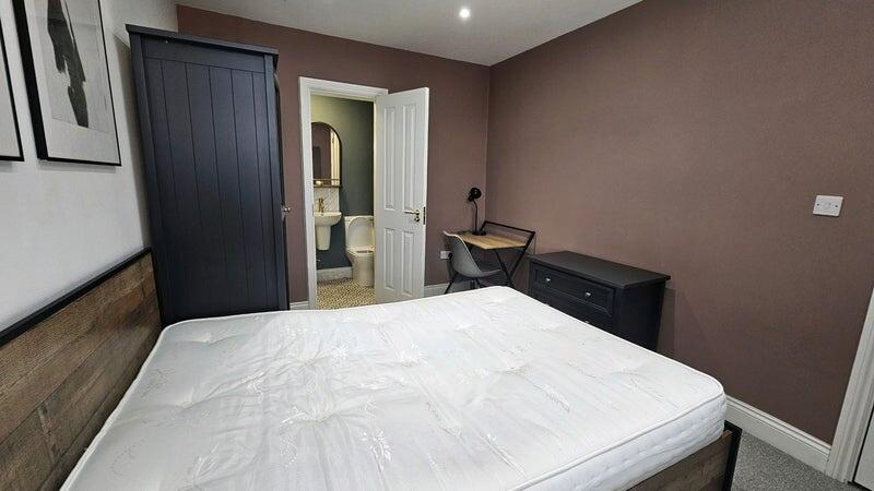 A cozy double bedroom featuring a sturdy wooden...