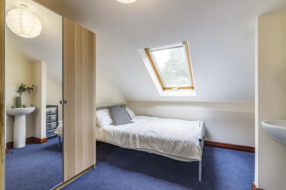 A neat and cozy single bedroom featuring a skyl...