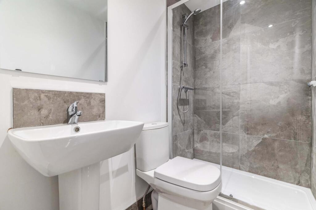 A modern, clean bathroom featuring a shower enc...