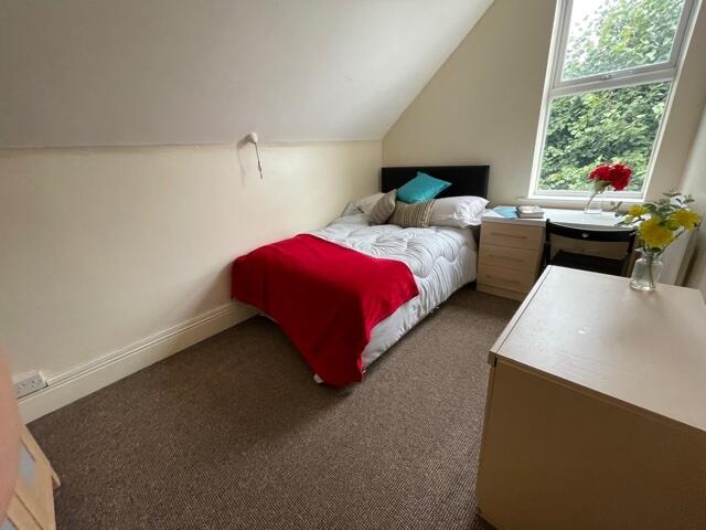 A cozy bedroom featuring a single bed draped wi...