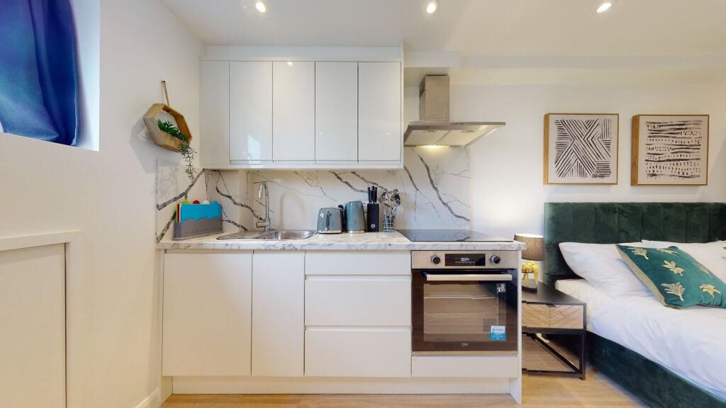 A modern studio space featuring a sleek white k...