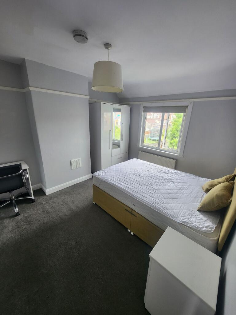 A bright double bedroom featuring a comfortable...