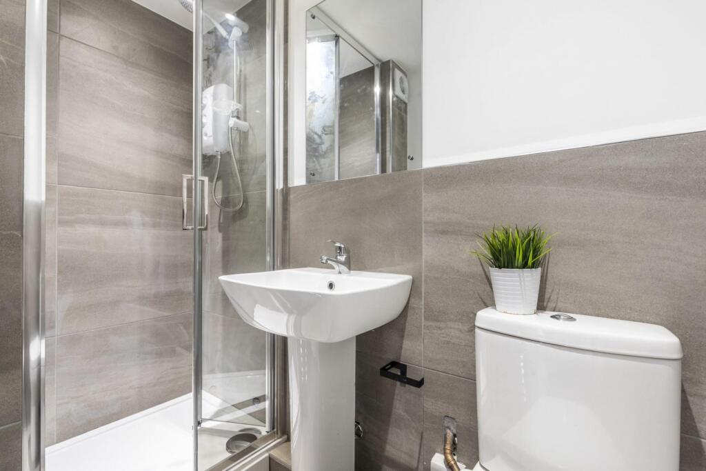 Bright, modern bathroom with a glass shower enc...