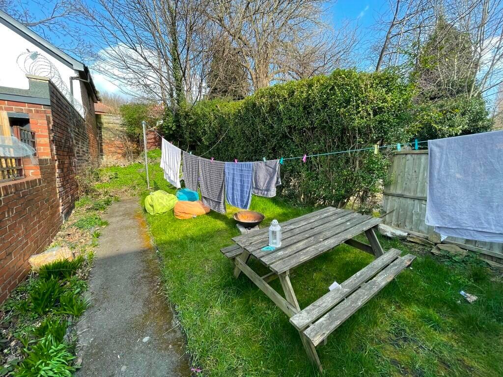 A sunny garden area featuring a wooden picnic b...