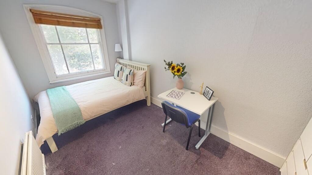 Cozy single bedroom featuring a neatly made bed...