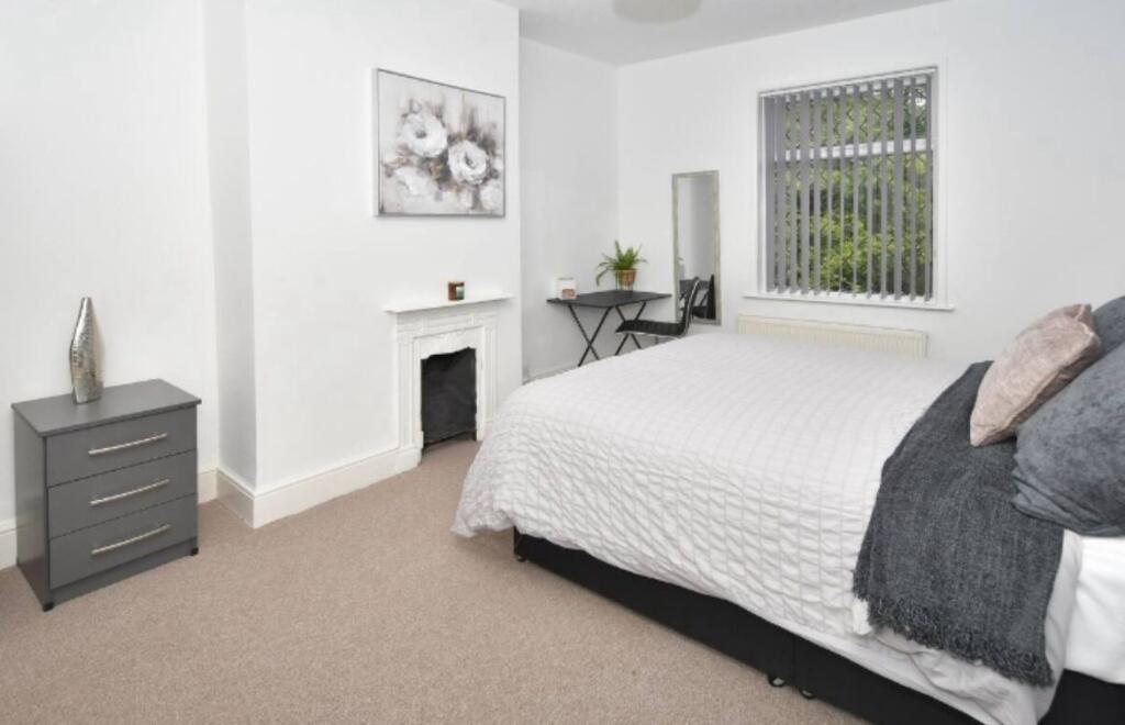 A bright, clean double bedroom featuring a comf...