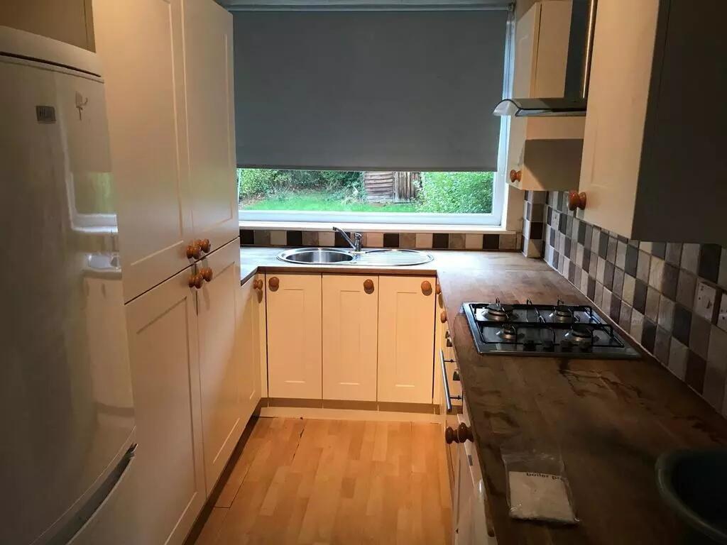 A compact kitchen featuring white cabinetry wit...