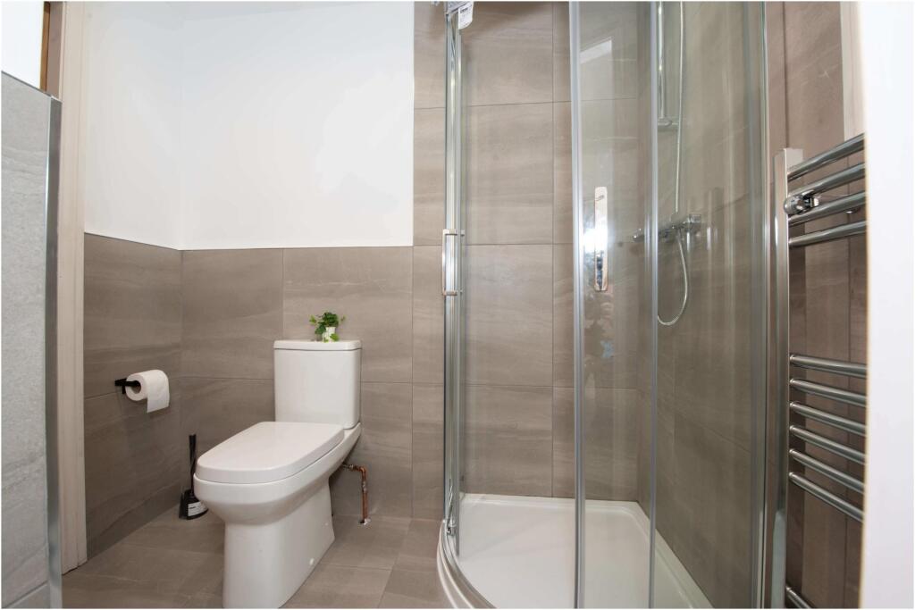A modern, tidy bathroom featuring a spacious sh...