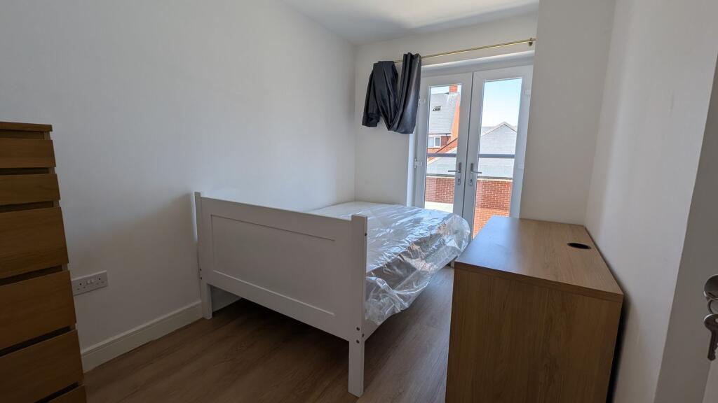 Bright, simply furnished bedroom with a white s...