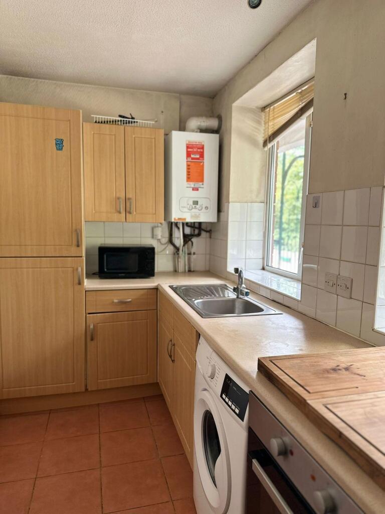 A compact kitchen featuring wooden cabinetry an...