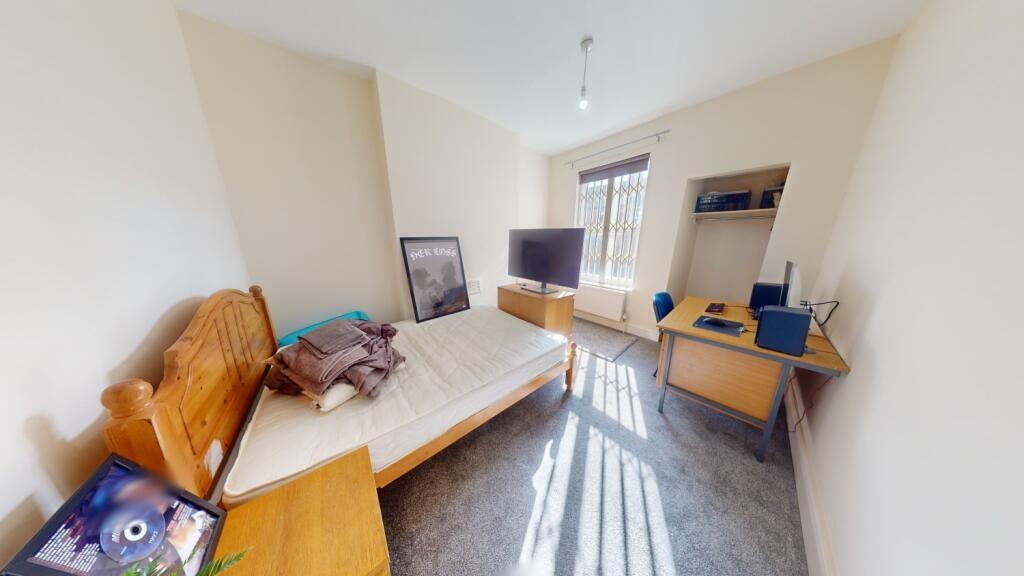 A cozy single bedroom featuring a wooden bed fr...