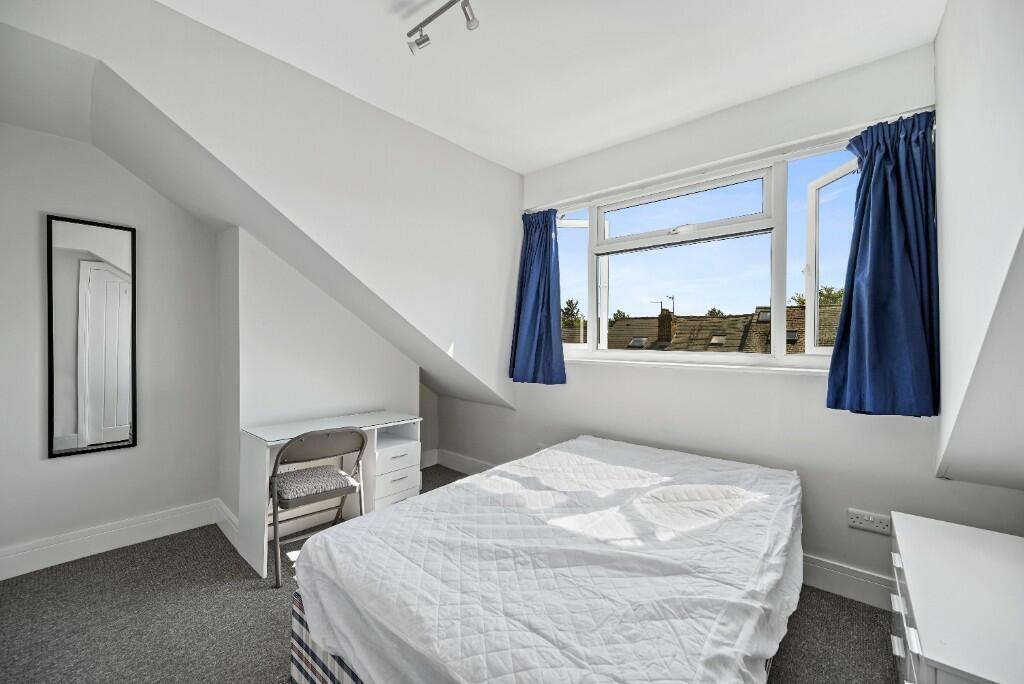Bright double bedroom featuring a well-lit wind...