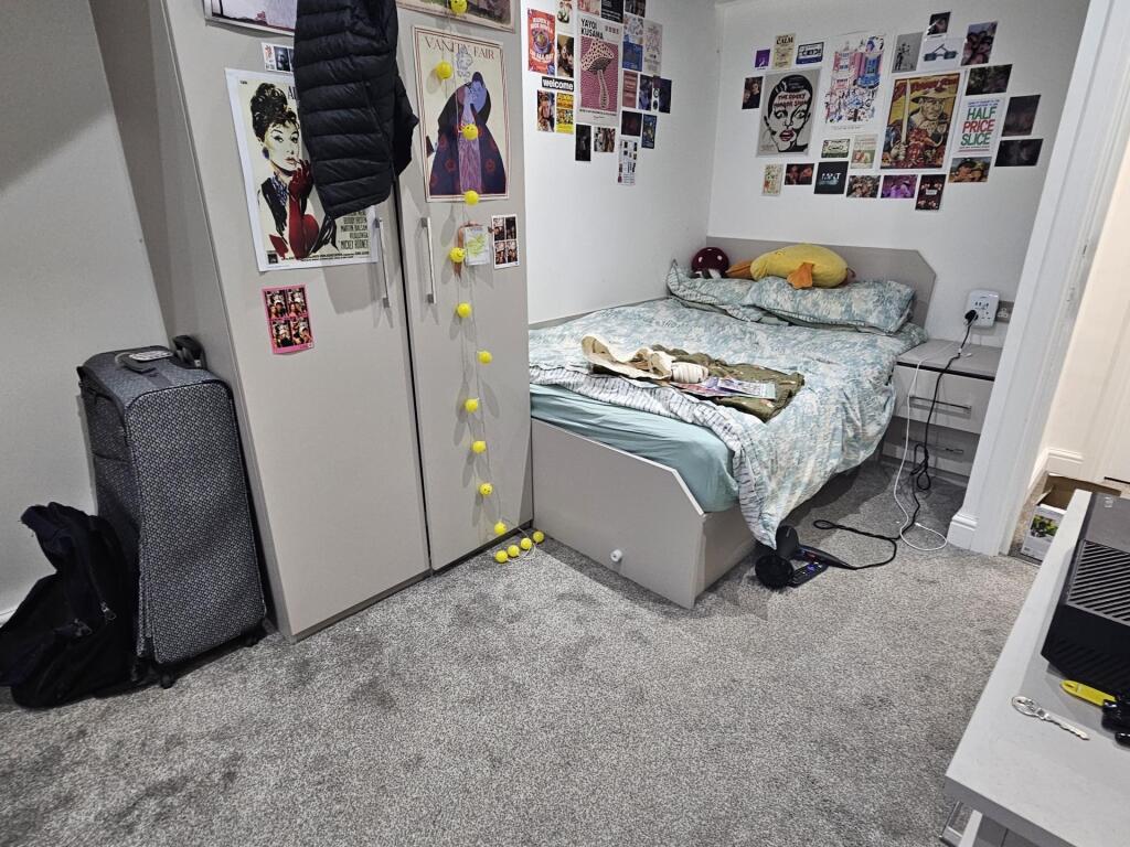 A cozy bedroom with a neatly made bed, personal...