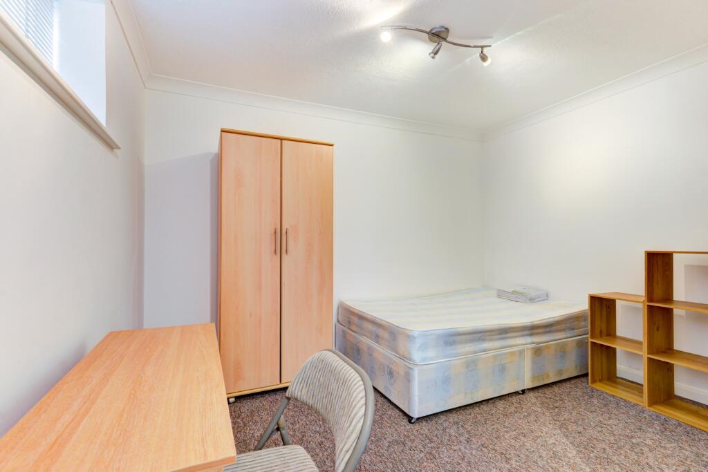 A tidy and simple bedroom featuring a single be...