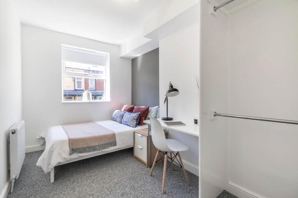 A bright and tidy bedroom featuring a comfortab...