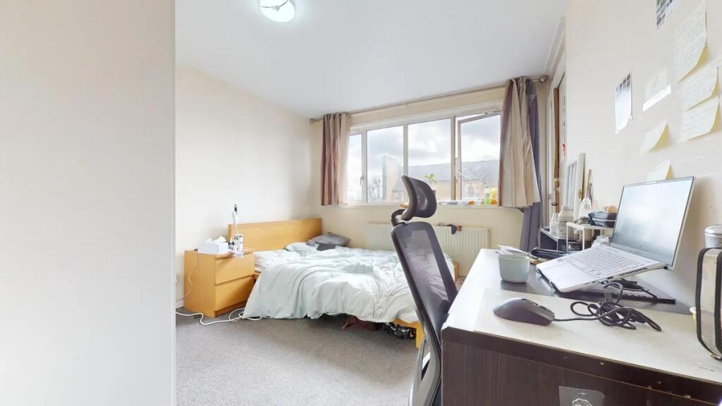 A cozy and well-lit bedroom featuring a large w...