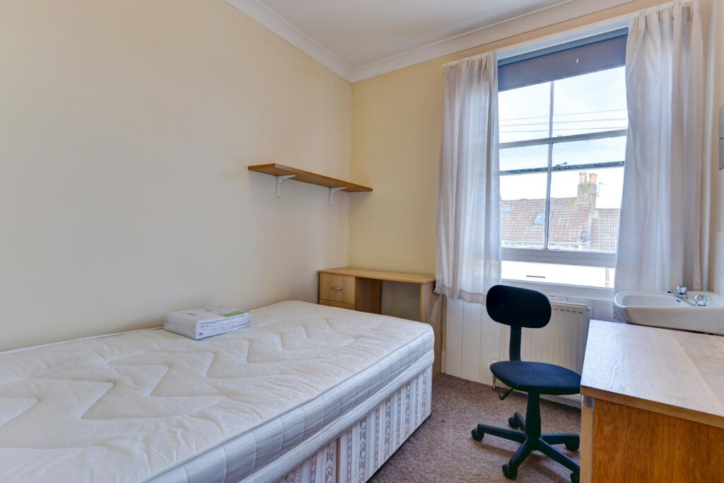 A cozy single bedroom with a comfortable bed, a...