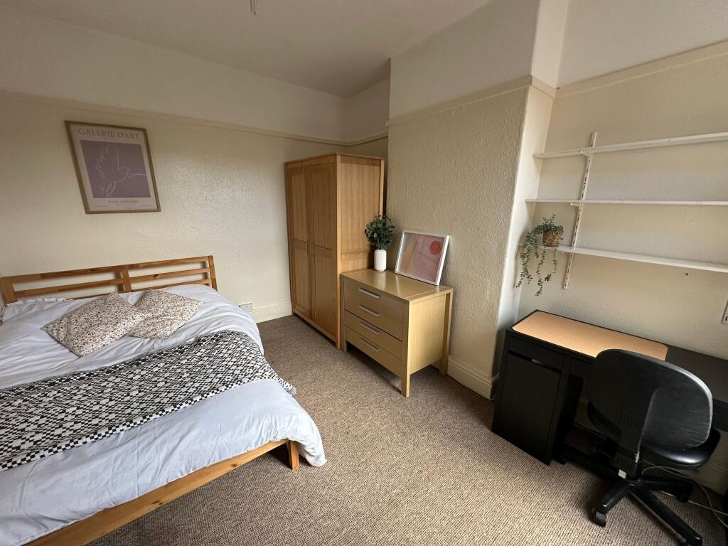 A cozy bedroom featuring a wooden bed frame wit...