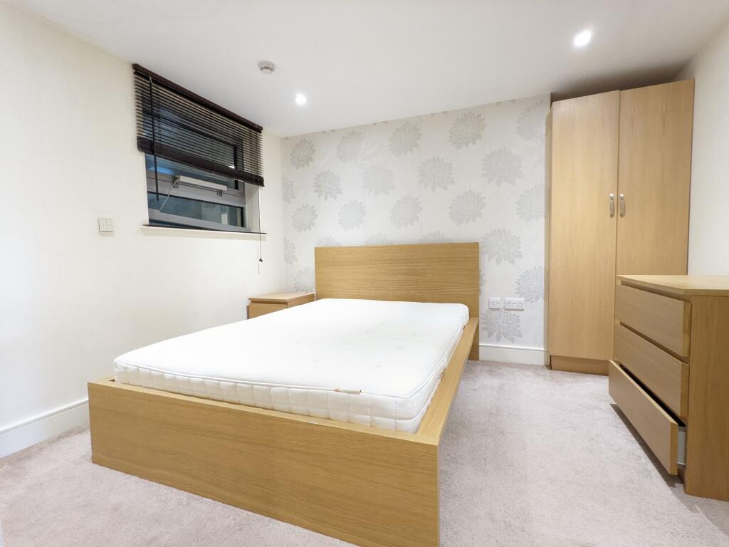 Bright, modern bedroom with a wooden bed frame,...