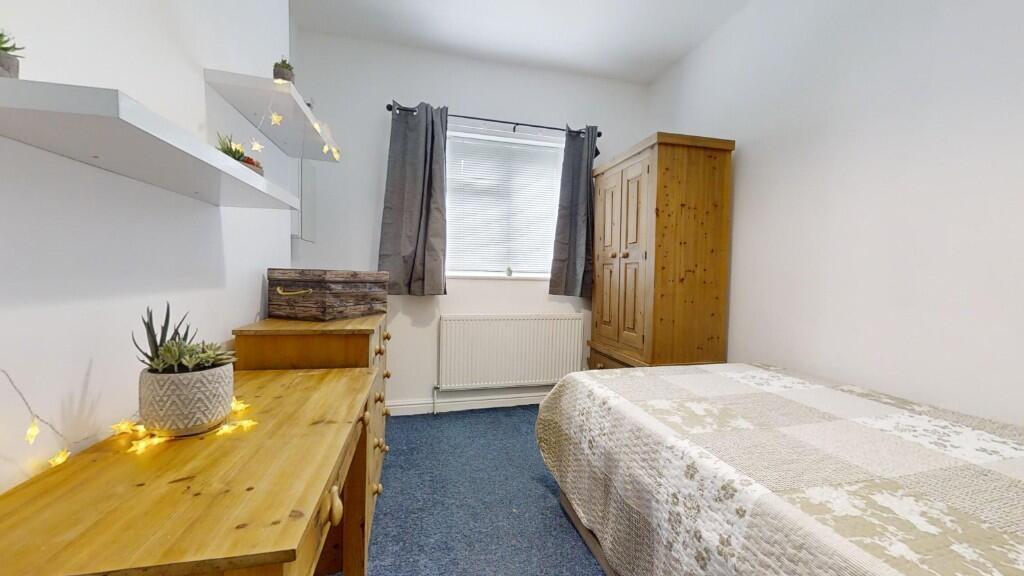 A cozy single bedroom featuring a neatly made b...