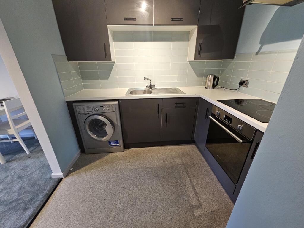 Modern compact kitchen with dark cabinetry, int...