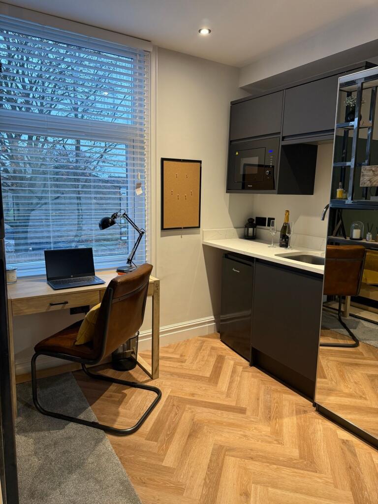 Modern kitchen area with sleek dark cabinetry, ...
