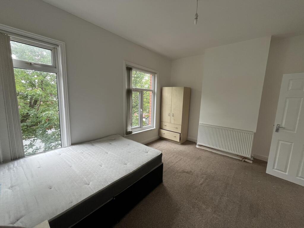 Bright double bedroom featuring large windows t...