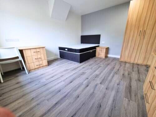 A clean, modern single bedroom featuring wood-e...