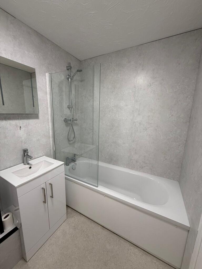 Modern bathroom featuring a sleek white bathtub...