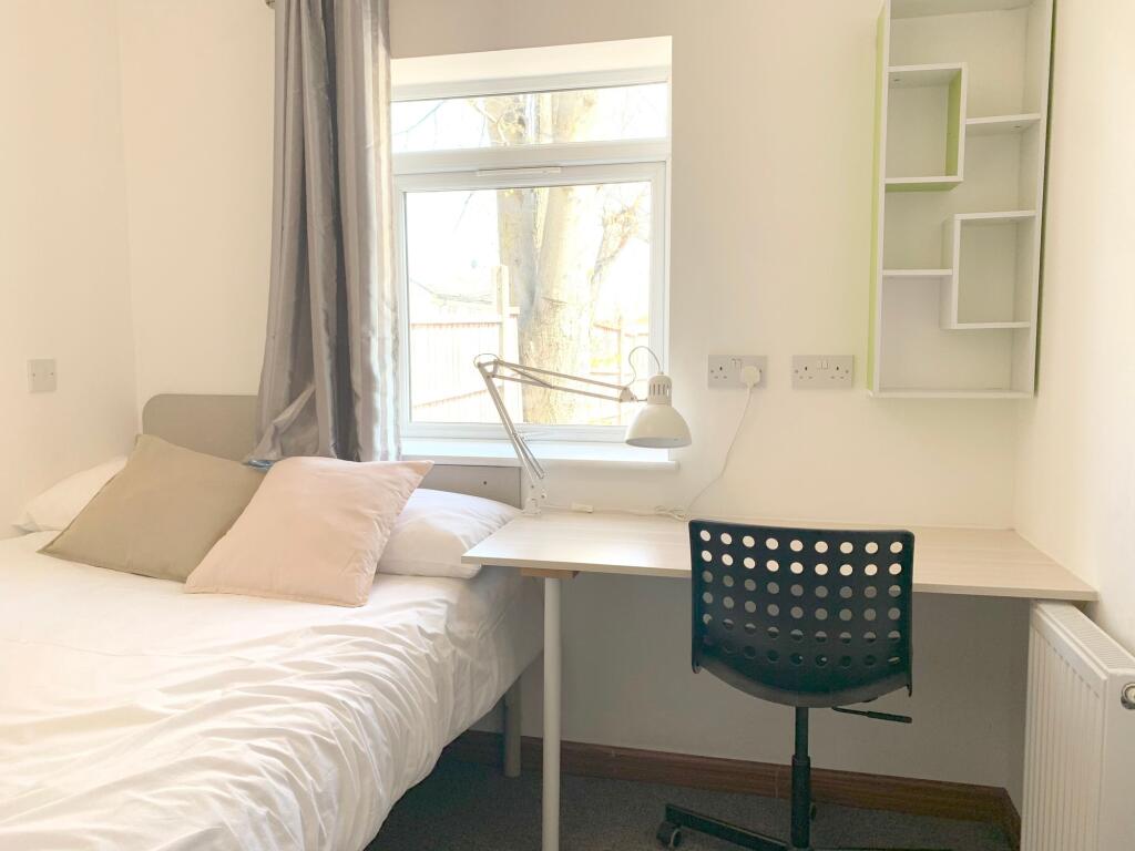 A bright and tidy single bedroom featuring a co...