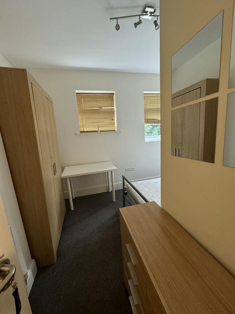 A bright, tidy bedroom with two small windows f...