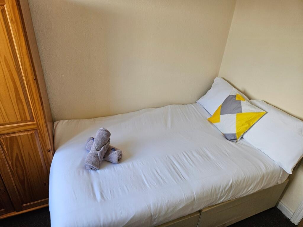 A cozy and tidy single bedroom featuring a comf...