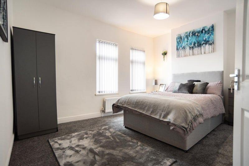 A spacious and tidy master bedroom featuring a ...