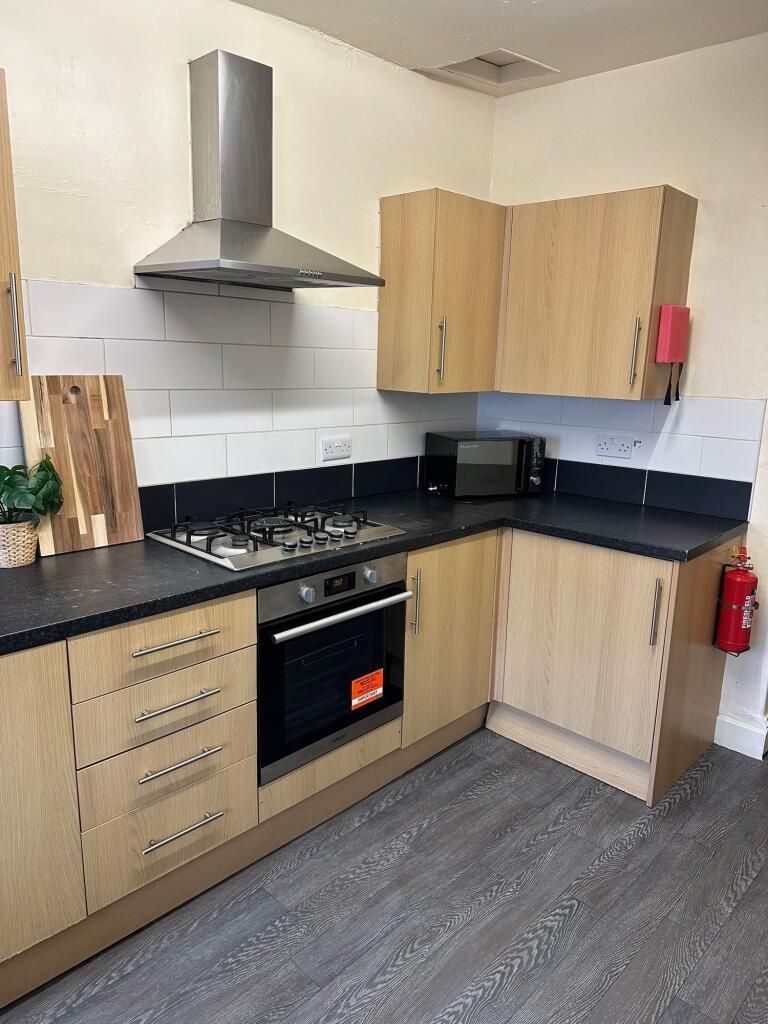 Modern kitchen with wooden cabinets, black coun...