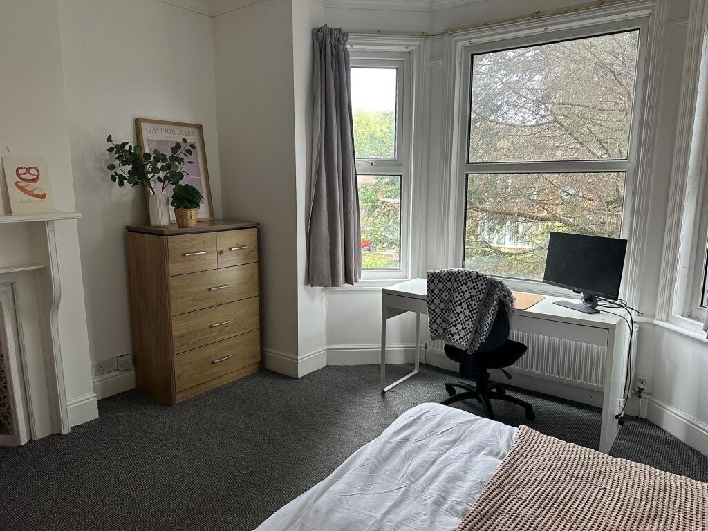 A well-lit bedroom featuring a large window wit...