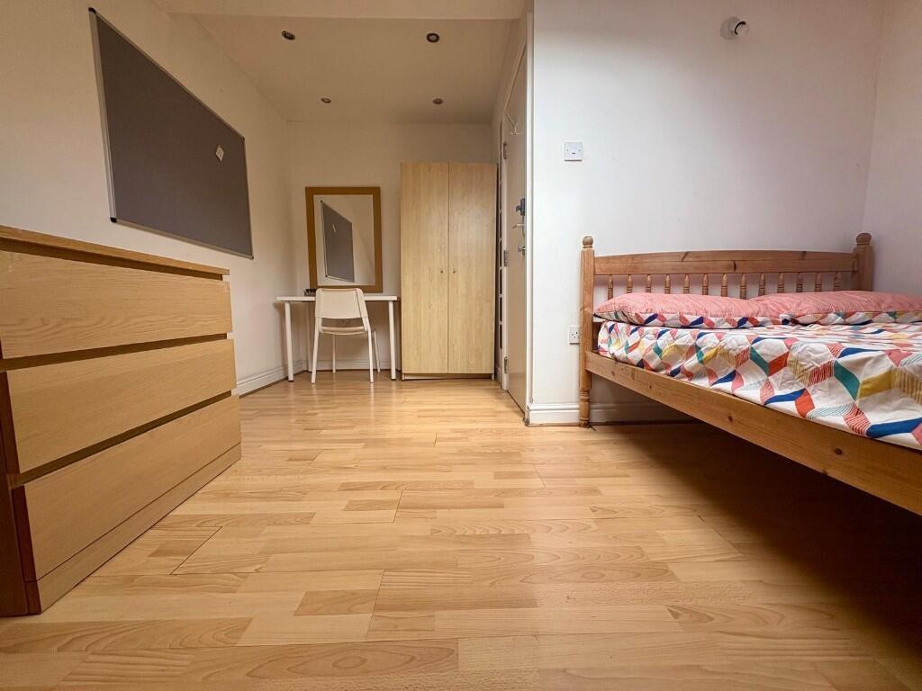 A neat and tidy bedroom with wooden flooring, f...