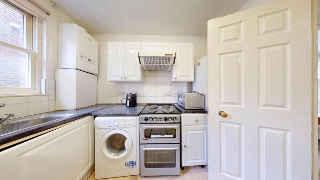 Bright and functional kitchen featuring white c...