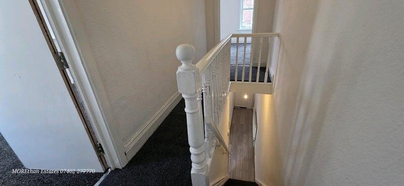 A bright and clean hallway with a white baniste...