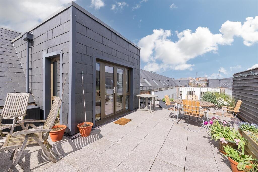 A spacious, sunny rooftop garden featuring ampl...