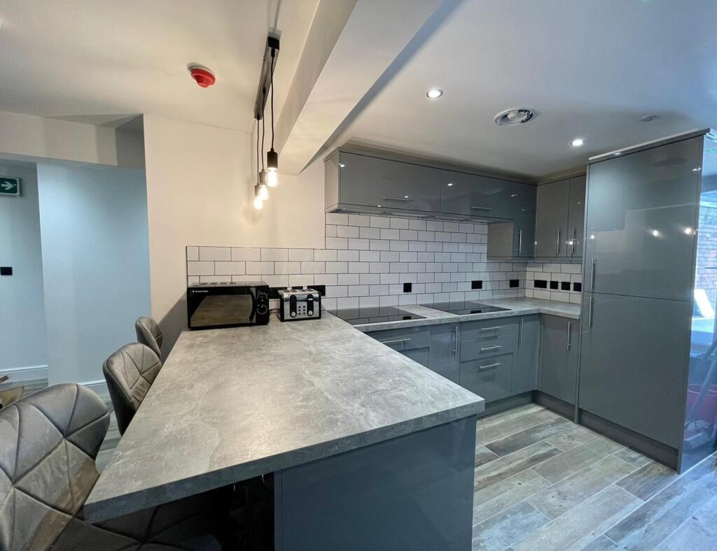 This modern kitchen features sleek grey cabinet...