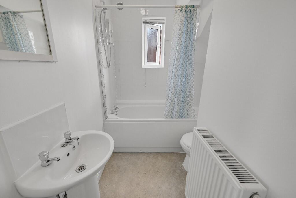 Bright and clean bathroom featuring a bath with...
