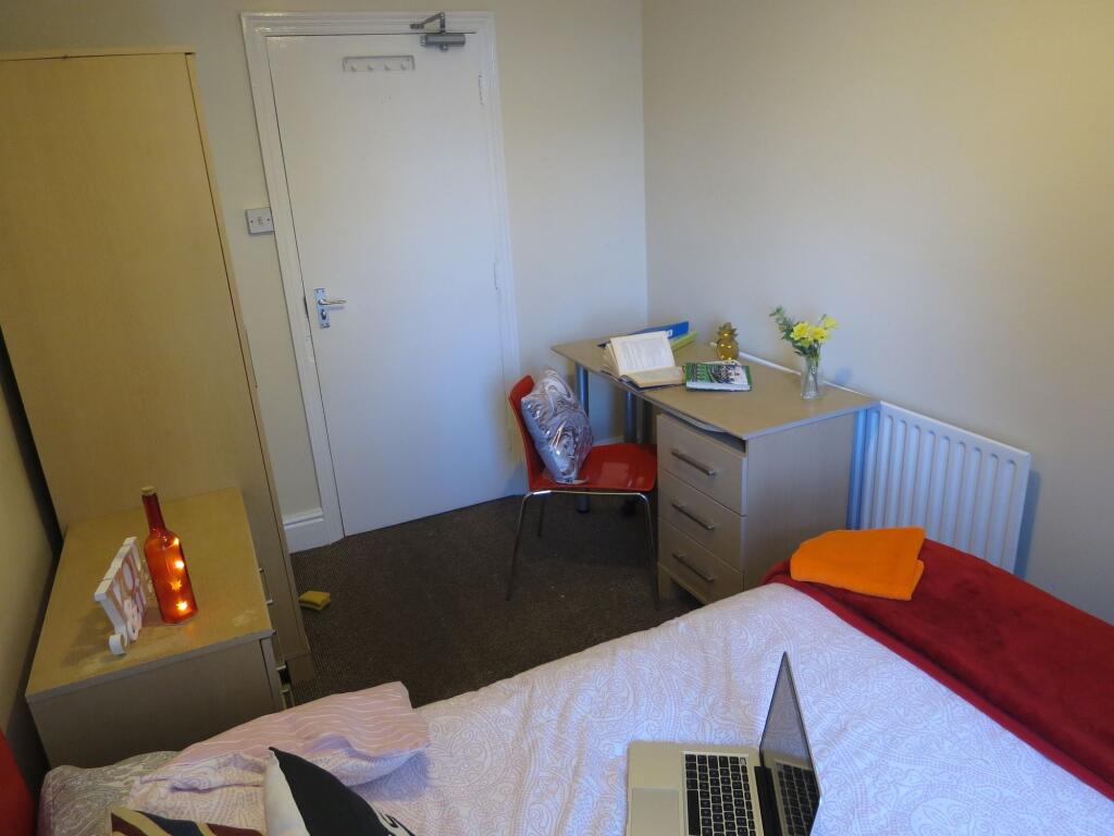 A well-kept bedroom featuring a single bed with...