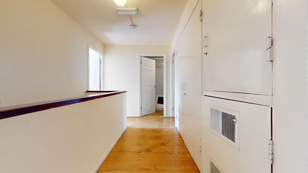 A bright and tidy hallway featuring polished wo...