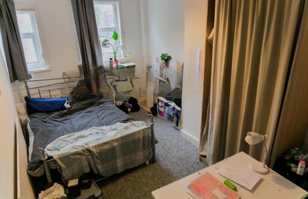 A cozy single bedroom featuring a comfortable b...